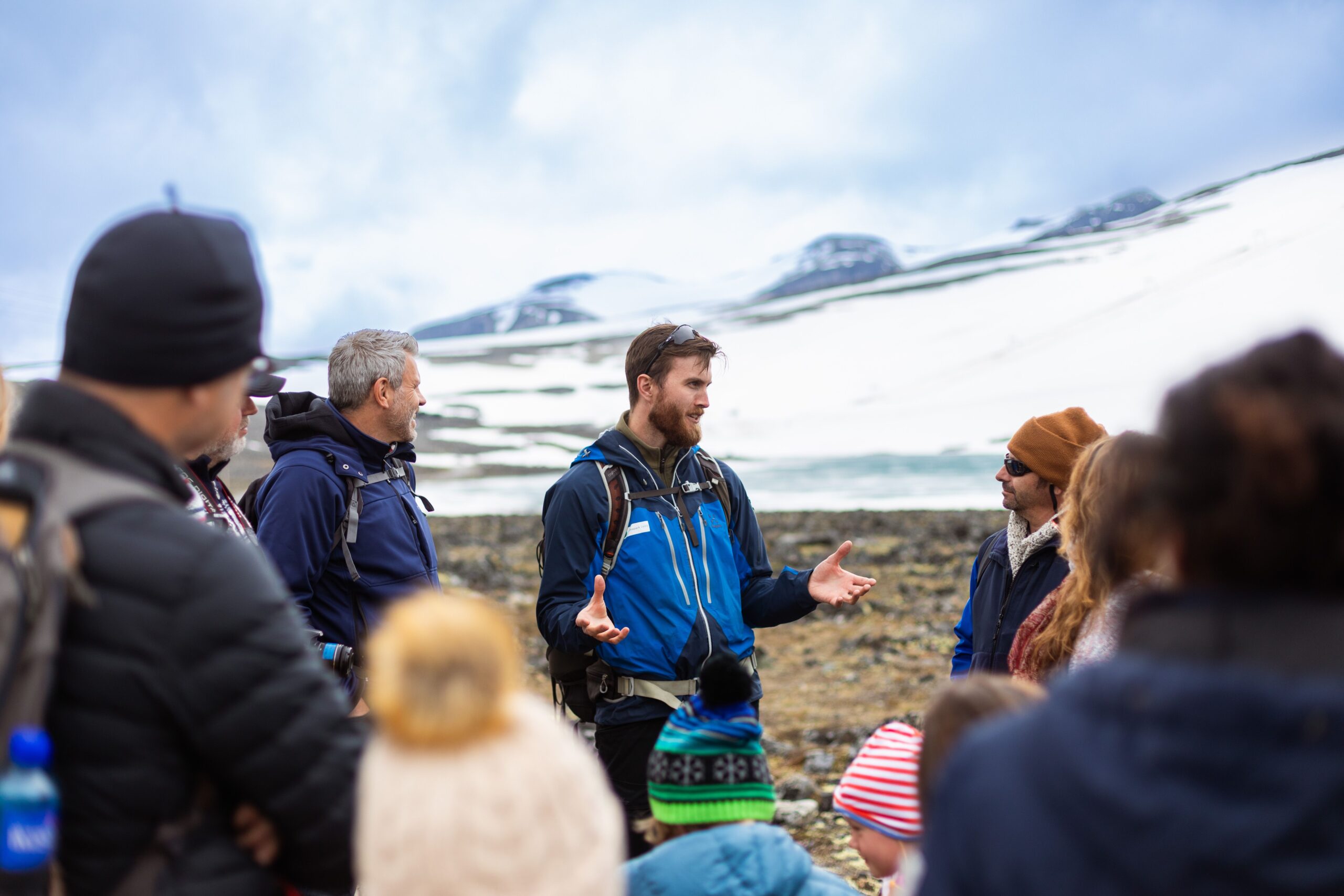 Ute på høgfjellet. Ein guide som snakkar framfor ei gruppe med folk.